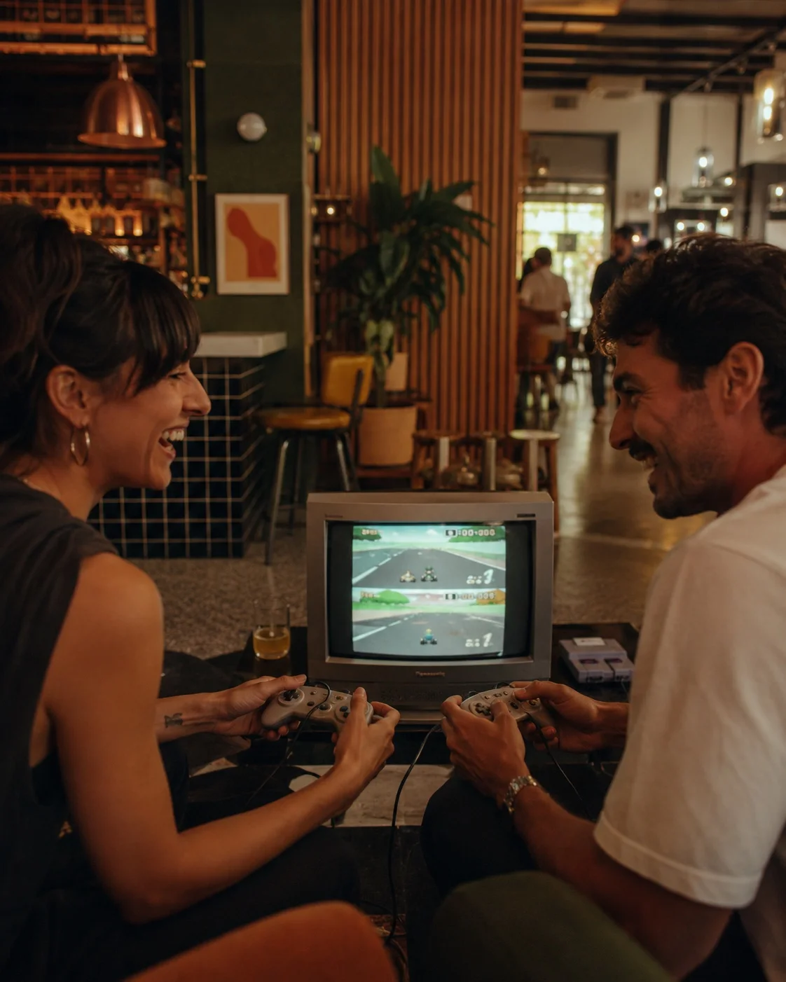 Two people playing Mario Kart on an SNES at ABXY